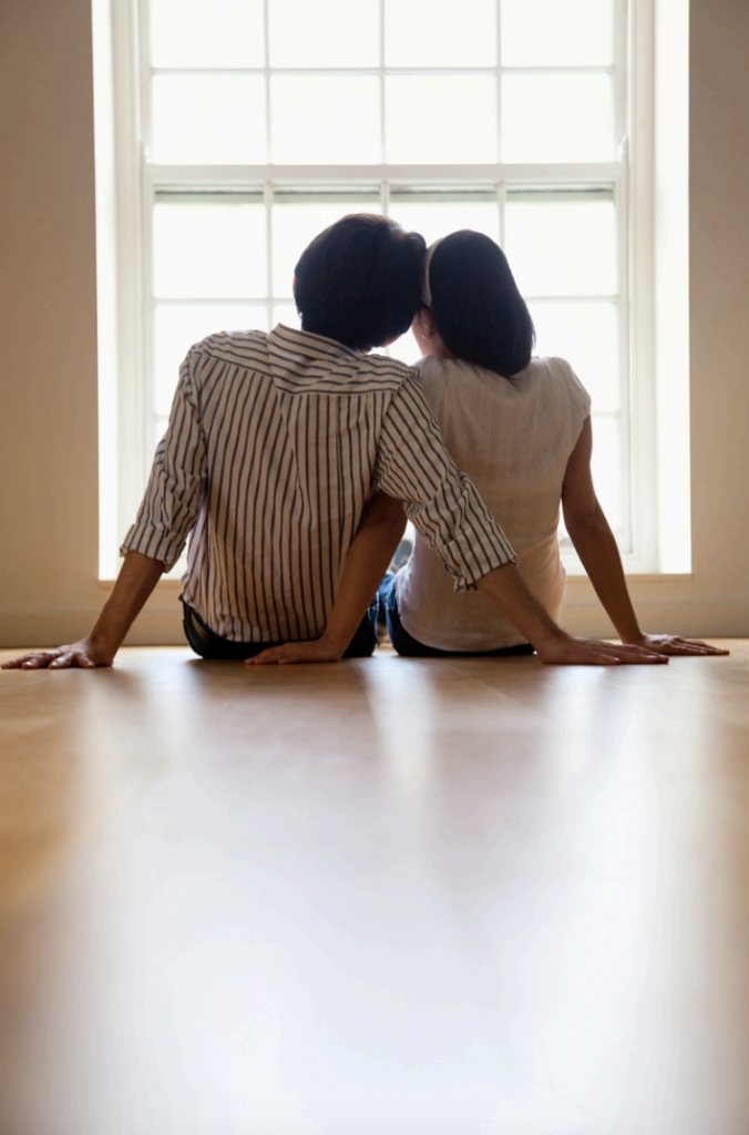 A couple, sitting closely, staring out a window.